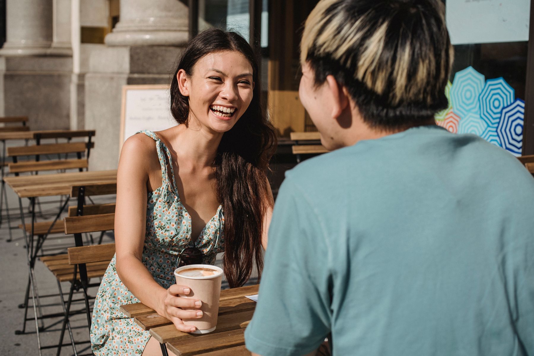 Two people laughing over coffee at a cafe table