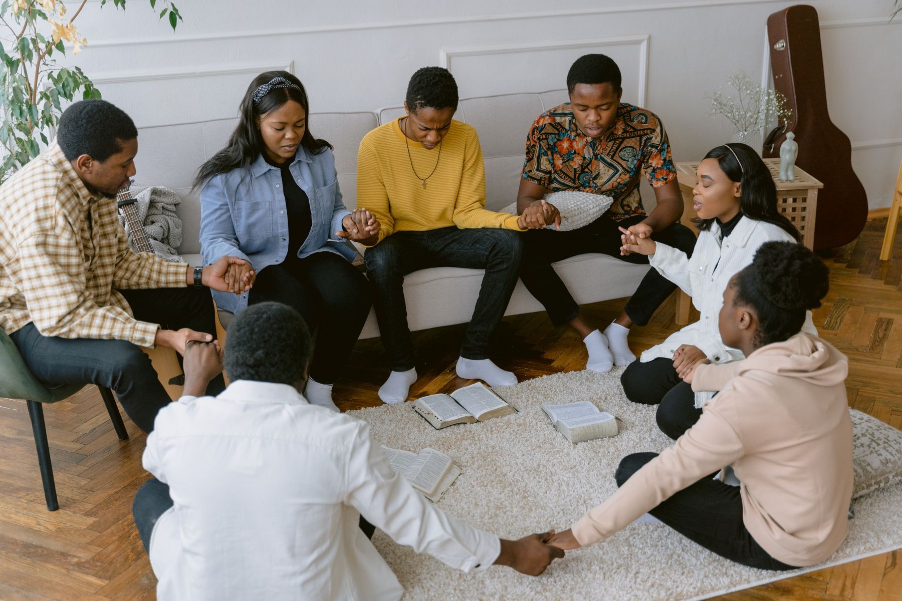 A home group holding hands to pray in a living room