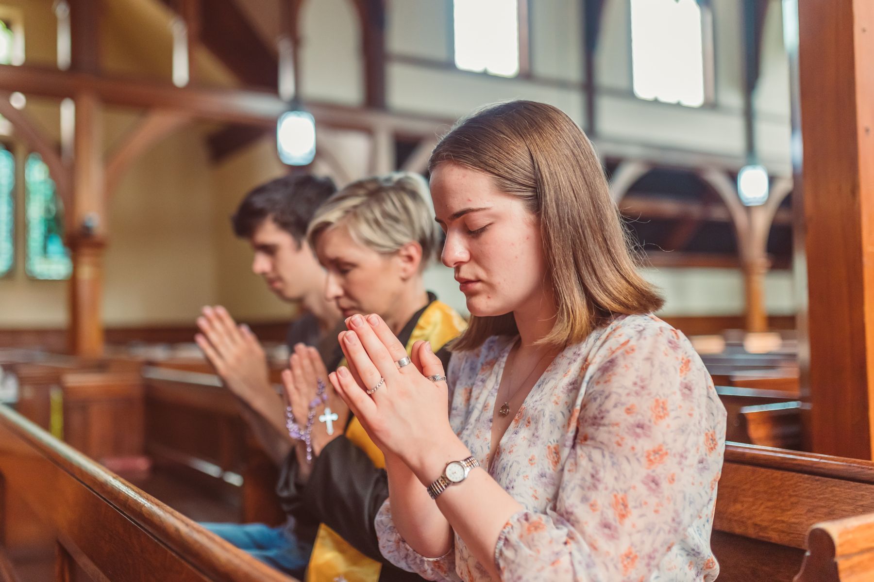 Three people praying in a pew