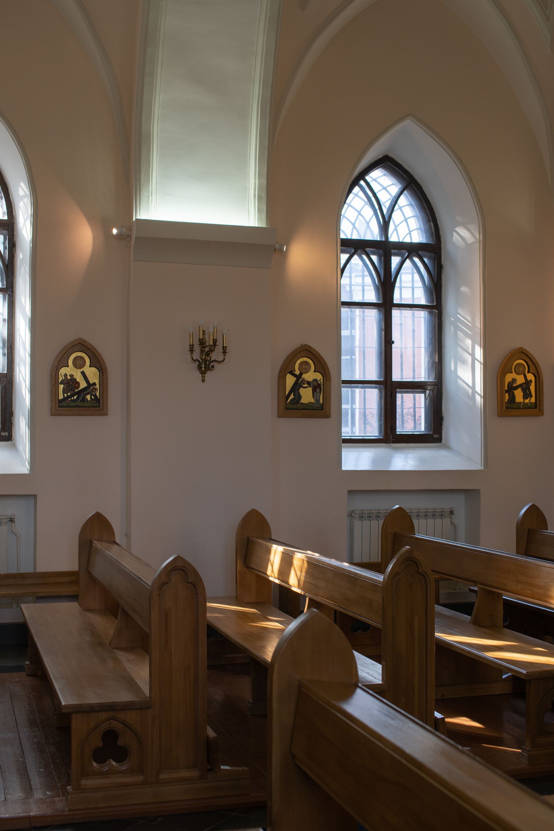 Wooden pews in sunlight beside tall arched windows